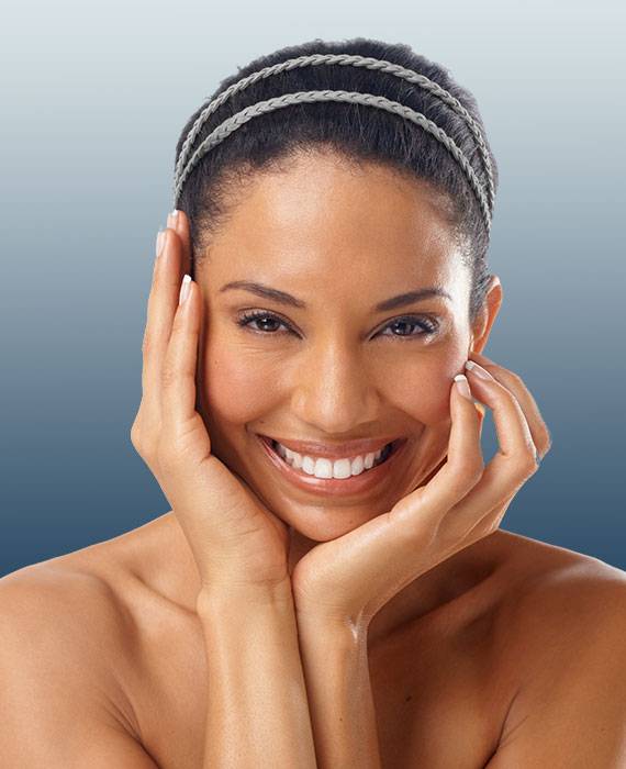 Beautiful African American woman with smooth skin smiling and touching her face | Skin Tightening